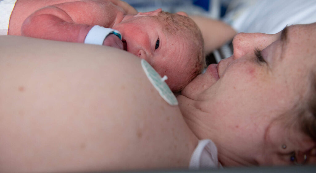 newborn baby crying after birth in mother’s arms