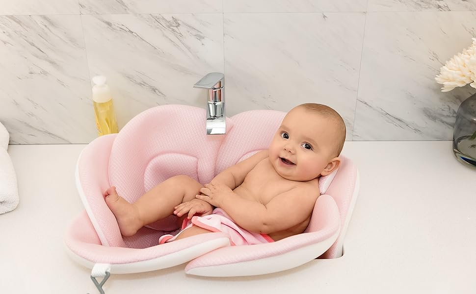 Baby in infant bathtub with parent supporting head